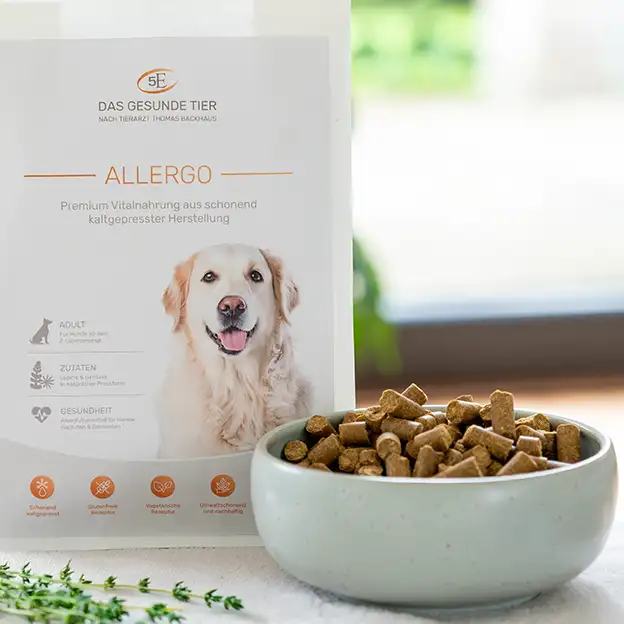 Verpackung von ALLERGO hypoallergenes Hundefutter neben einem Napf mit kaltgepressten Futterstücken.