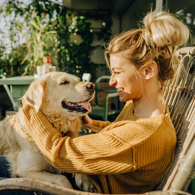 Frau verbringt einen entspannten Sommertag mit ihrem Golden Retriever auf dem Balkon..