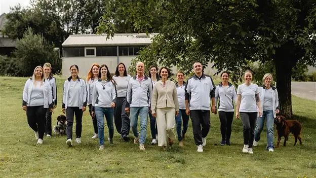 Team von Das Gesunde Tier gemeinsam mit Hunden auf einer Wiese im Freien.