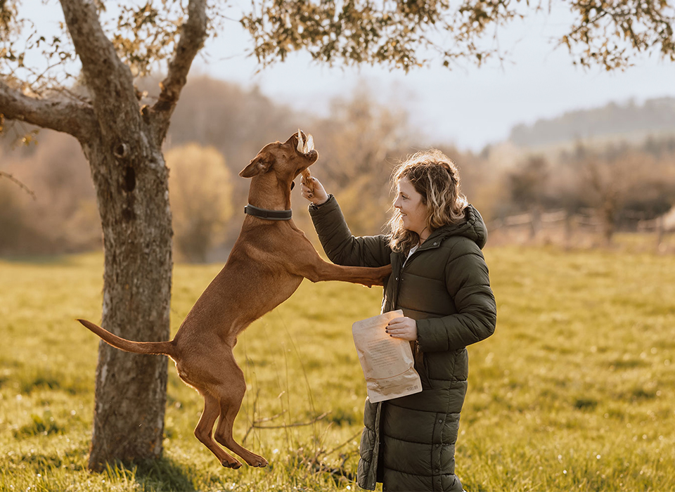 Frau spielt draußen mit ihrem Hund.